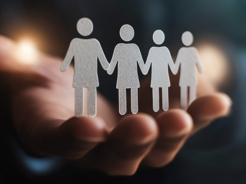 In this illustration a hand holds four stick figures, representing control over people's lives.