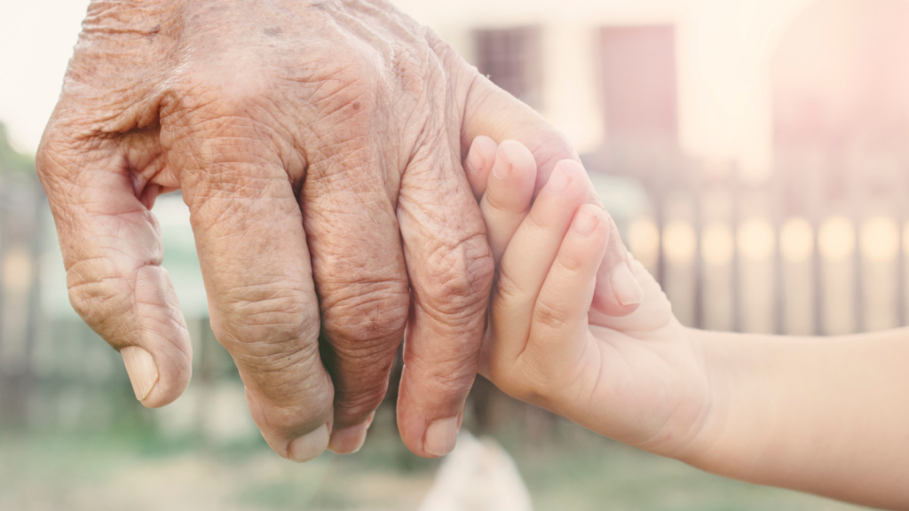 an older adult holding hands with their grandkid